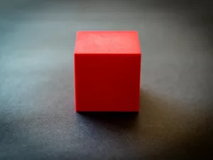 red-cube-sitting-on-dark-surface.jpeg