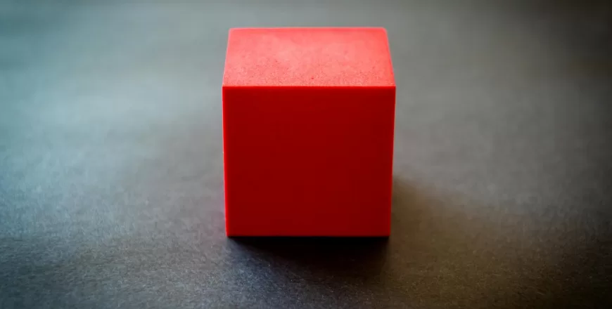 red-cube-sitting-on-dark-surface.jpeg